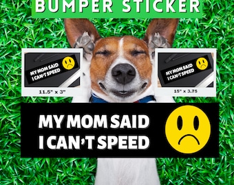 May include: A black and yellow bumper sticker with the text "My Mom Said I Can't Speed" and a yellow cartoon face with a sad expression. The sticker is shown on a green grassy background with a dog's head in the middle.