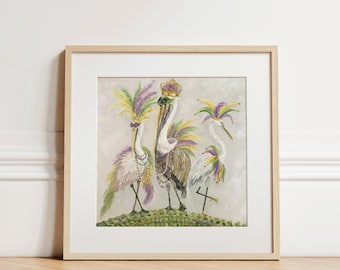 Puede incluir: Una impresión enmarcada que presenta tres pelícanos adornados con tocados de plumas al estilo Mardi Gras y una corona. Las aves se alzan sobre una superficie verde, con un fondo neutro. La obra de arte se exhibe en un marco de madera clara.