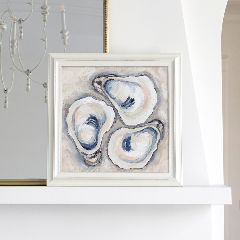 May include: Square framed artwork featuring an abstract painting of three oyster shells. The shells are painted in shades of white, blue, and beige, with visible brushstrokes. The artwork is displayed in a white frame.