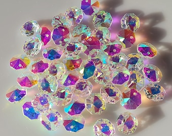 Puede incluir: Una colección de cuentas de vidrio iridiscente en varios tonos de rosa, morado, azul y verde. Las cuentas son facetadas y tienen una forma hexagonal.