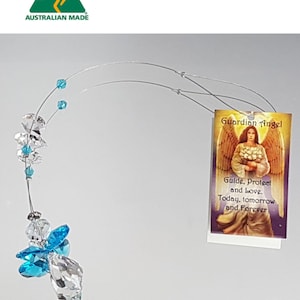 Puede incluir: Un adorno colgante decorativo con un ángel de cristal con cuentas facetadas transparentes y azul brillante. El adorno está unido a una tarjeta rectangular con una ilustración de un ángel y el texto: Guardian Angel, Guide, Protect and love. Today, tomorrow and Forever.