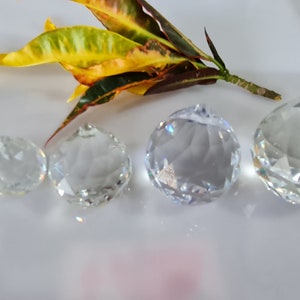 May include: Five clear crystal prisms of varying sizes, arranged in a row from smallest to largest on a white surface.