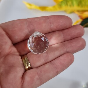 May include: A clear crystal ball with many facets, held in a hand.