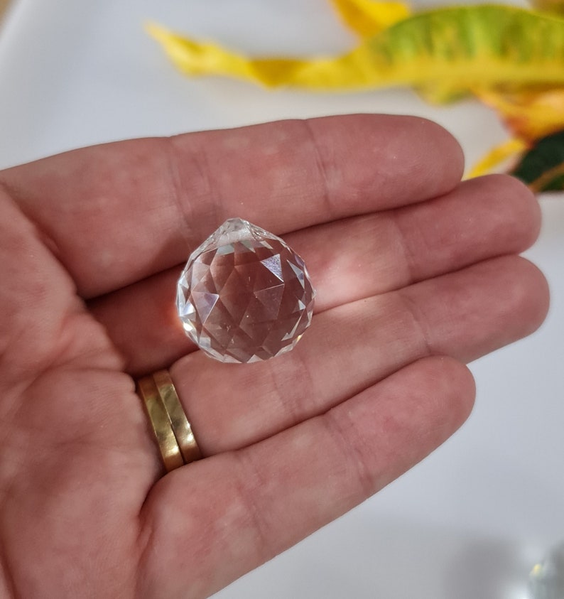 May include: A clear crystal ball with many facets, held in a hand.