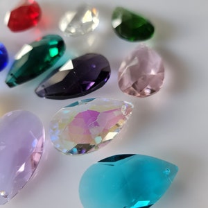May include: Assortment of crystal teardrop shaped pendants in various colors, including clear, red, green, purple, pink, blue, and iridescent.