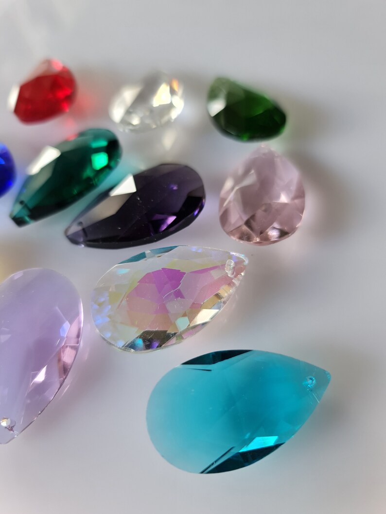 May include: Assortment of crystal teardrop shaped pendants in various colors, including clear, red, green, purple, pink, blue, and iridescent.