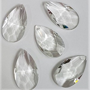 May include: Five clear glass teardrop-shaped crystal prisms with a hole at the top for hanging.