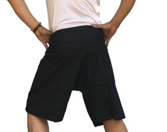 May include: Black cotton shorts with a unique design, featuring a wide waistband and a loose, flowing fit. The shorts are shown on a person standing on a green surface.