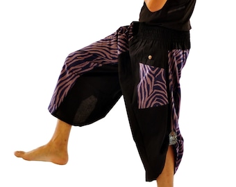 May include: A person wearing black pants with a purple and white zebra print design. The pants have a drawstring waist and a loose fit.