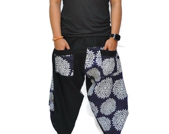 May include: A person wearing a black sleeveless shirt and black and blue patterned pants with white flowers. The pants have a loose fit and are gathered at the ankles.