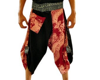 May include: A person wearing black pants with a red and white floral pattern. The pants have a black waistband with a silver and black patterned belt. The person is wearing a black sleeveless shirt.