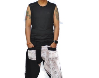 May include: A person wearing a black sleeveless shirt and black pants with white lace detailing. The pants have a loose fit and are gathered at the ankles.