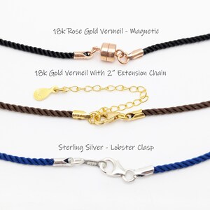 May include: Close-up of three necklace clasps. The top one is 18k rose gold vermeil with a magnetic clasp on a black cord. The middle one is 18k gold vermeil with a 2" extension chain on a brown cord. The bottom one is sterling silver with a lobster clasp on a blue cord.