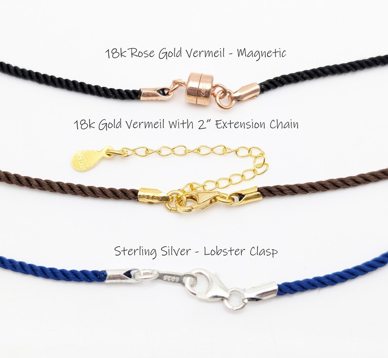 May include: Close-up of three necklace clasps. The top one is 18k rose gold vermeil with a magnetic clasp on a black cord. The middle one is 18k gold vermeil with a 2" extension chain on a brown cord. The bottom one is sterling silver with a lobster clasp on a blue cord.
