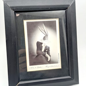 Pu&ograve; includere: Stampa incorniciata in nero con Bugs Bunny in smoking, con guanti bianchi e papillon. La stampa &egrave; firmata da Alan M. Broder e Perry Olds. La cornice &egrave; rettangolare e in legno.