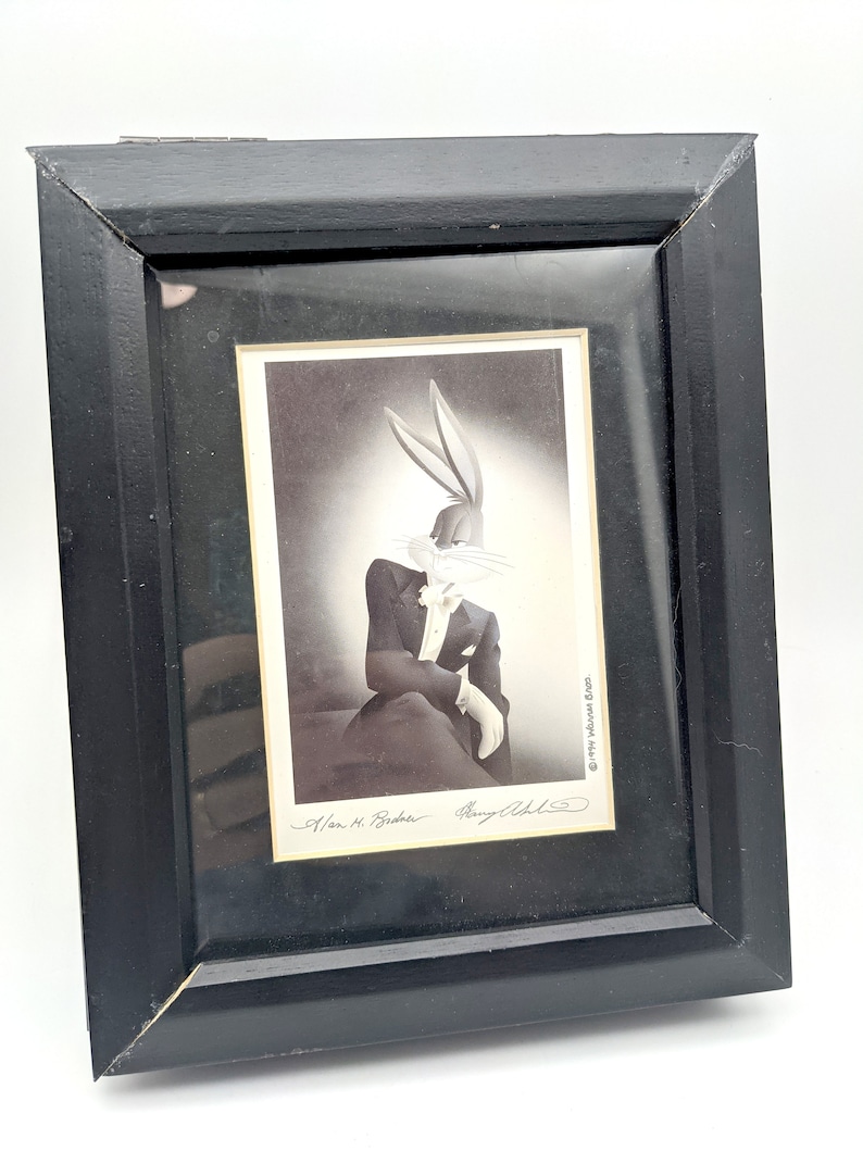 Pu&ograve; includere: Stampa incorniciata in nero con Bugs Bunny in smoking, con guanti bianchi e papillon. La stampa &egrave; firmata da Alan M. Broder e Perry Olds. La cornice &egrave; rettangolare e in legno.