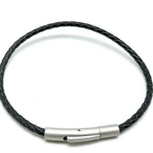 May include: A black leather bracelet with a silver clasp.
