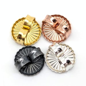 May include: Four circular earring backs with a scalloped edge and a central post loop. The set includes one gold-tone, one rose gold-tone, one dark gunmetal-tone, and one silver-tone piece. Each back is stamped with the text 925 on the loop.