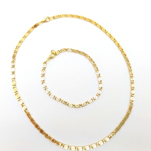 May include: A gold chain necklace and bracelet set with a delicate, intricate design. The chain is made of small, linked, oval-shaped pieces.