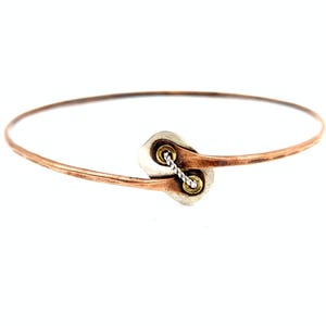 May include: A hammered copper bangle bracelet featuring a central silver-toned rectangular element with rounded corners. The copper band ends are secured to the silver piece with two brass-toned rivets and a twisted silver-toned wire connector.