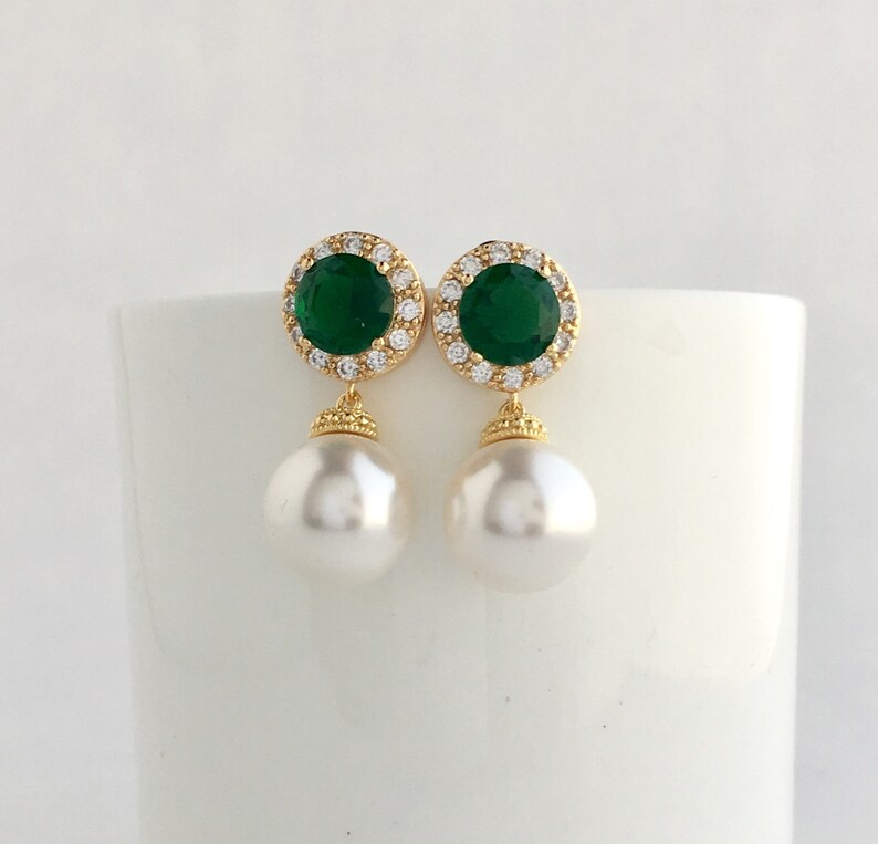 Puede incluir: Pendientes de oro con una piedra preciosa verde rodeada de piedras m&aacute;s peque&ntilde;as transparentes y una perla blanca.