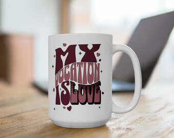 Könnte beinhalten: Weiße Keramik-Kaffeetasse mit einem rosa und burgunderfarbenen Design, auf dem "My Vocation Is Love" steht.