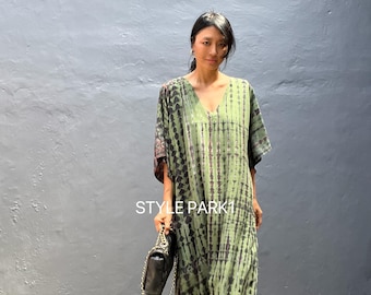 May include: A woman wearing a green and black tie-dye maxi dress with a black purse. The dress has a V-neck and short sleeves. The text "STYLE PARK1" is visible on the dress.