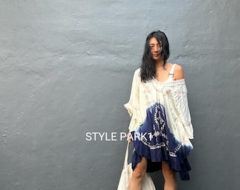 May include: A cream and navy blue dip-dyed tunic dress featuring intricate white embroidery, ruffled sleeves, and a loose silhouette. The garment displays the text STYLE PARK in white lettering. A plain white tote bag is carried alongside the dress.