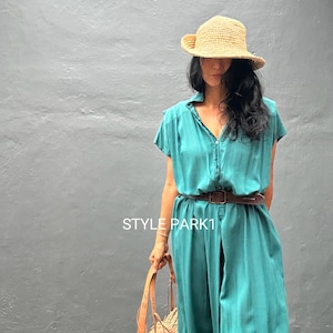 Peut inclure: Une robe boutonn&eacute;e sarcelle &agrave; manches courtes avec une ceinture en cuir marron fonc&eacute; &agrave; la taille. La robe porte le texte STYLE PARK1. Un chapeau de paille et un sac fourre-tout en paille tress&eacute;e avec des anses en cuir compl&egrave;tent l'ensemble.