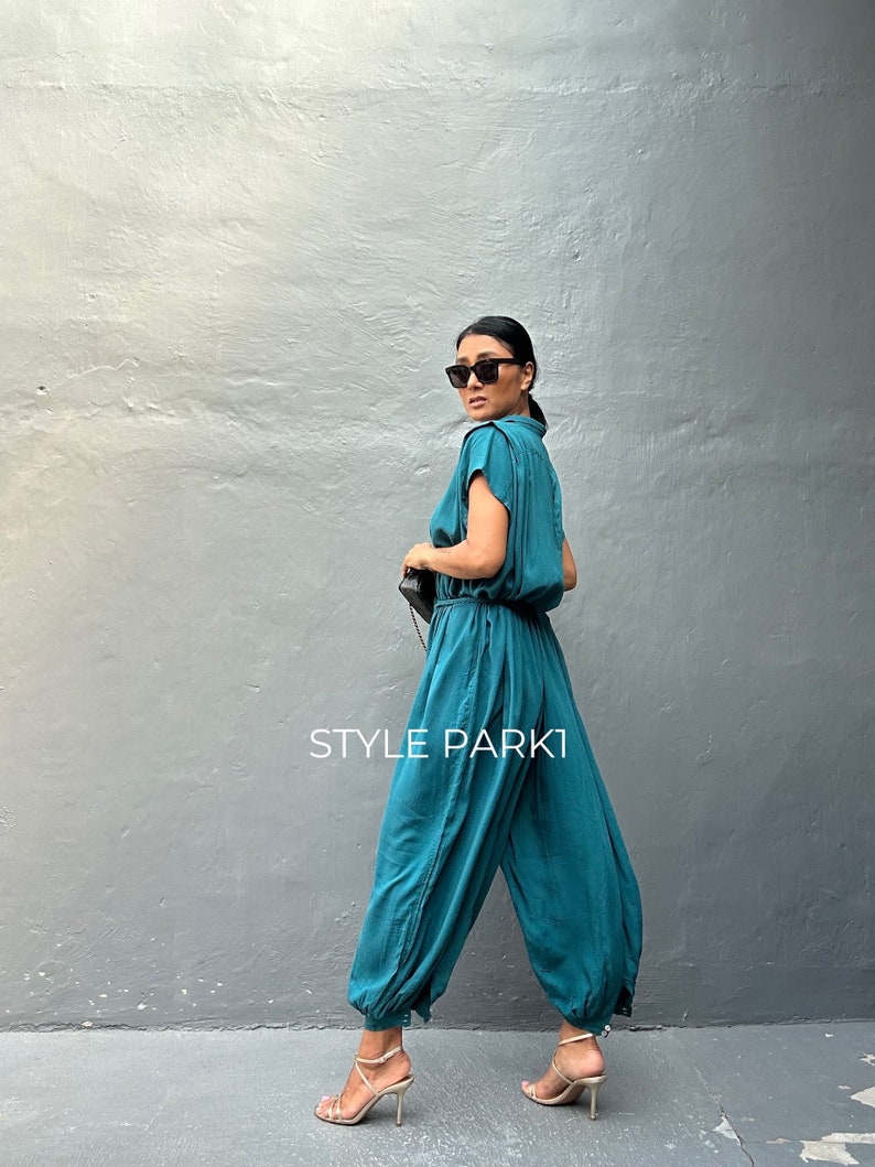 Peut inclure: Une combinaison bleu sarcelle &agrave; manches courtes, taille cintr&eacute;e et jambes fusel&eacute;es resserr&eacute;es aux chevilles. Le v&ecirc;tement pr&eacute;sente un corsage boutonn&eacute; et porte l'inscription STYLE PARK1. Le mod&egrave;le comprend un col et des poches lat&eacute;rales.