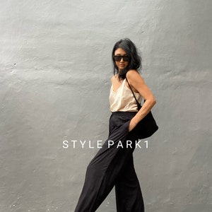 May include: A woman wearing a black top and wide-leg black pants with a black bag over her shoulder. The text "STYLE PARK1" is visible in the image.