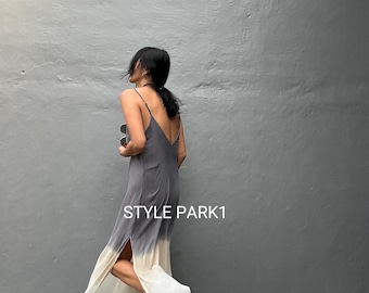 May include: A gray and white ombre slip dress with spaghetti straps and a high slit. The dress is floor-length and has the text "STYLE PARK1" on the side. The model is wearing gold strappy heels.
