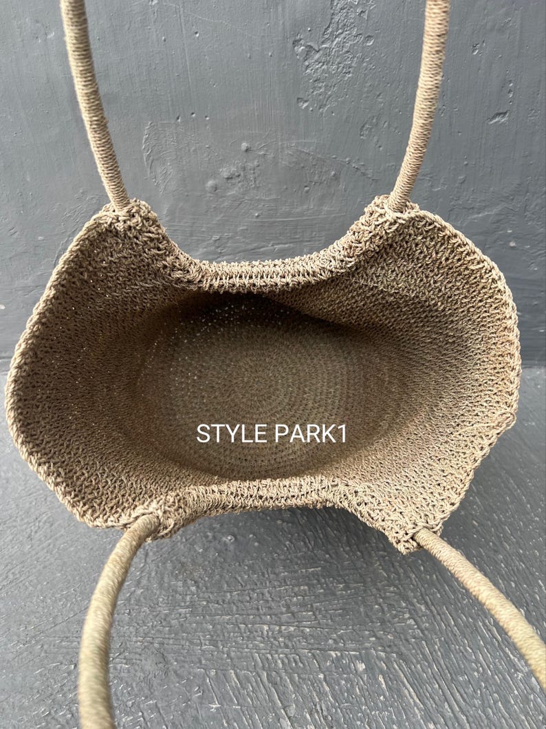 Pu&ograve; includere: Una borsa tote in crochet beige con due manici. La borsa &egrave; vuota e l'interno &egrave; visibile. Il testo "STYLE PARK1" &egrave; visibile all'interno della borsa.