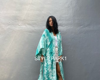 May include: A long, teal blue kimono with a white and teal pattern. The kimono has a tie belt and long sleeves. The model is wearing the kimono with a pair of white shorts and gold sandals. The text "STYLE PARK1" is visible on the image.