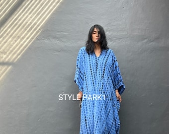 Puede incluir: Un vestido largo y fluido de color azul con un estampado tie-dye. El vestido tiene cuello en V y mangas anchas. El texto "STYLE PARK1" es visible en el vestido. El fondo es una pared gris con sombras.