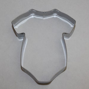 May include: A silver metal cookie cutter shaped like a baby onesie.