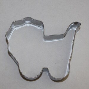 May include: A silver metal cookie cutter shaped like a baby carriage.