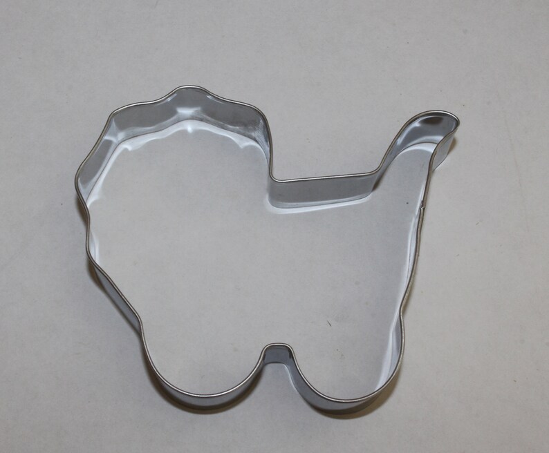 May include: A silver metal cookie cutter shaped like a baby carriage.