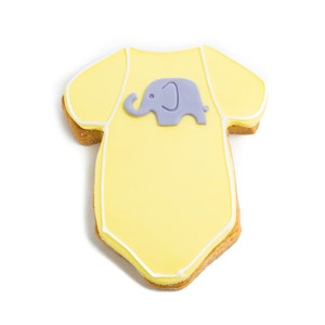 May include: A yellow baby onesie cookie decorated with white icing and a purple fondant elephant.