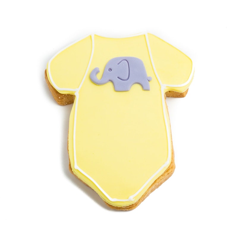 May include: A yellow baby onesie cookie decorated with white icing and a purple fondant elephant.