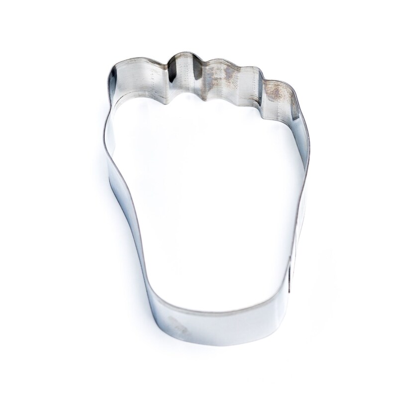 May include: A silver metal cookie cutter shaped like a foot.