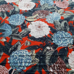 May include: Red fabric with a floral print featuring blue, white, and pink flowers. The flowers are stylized and have a vintage look.