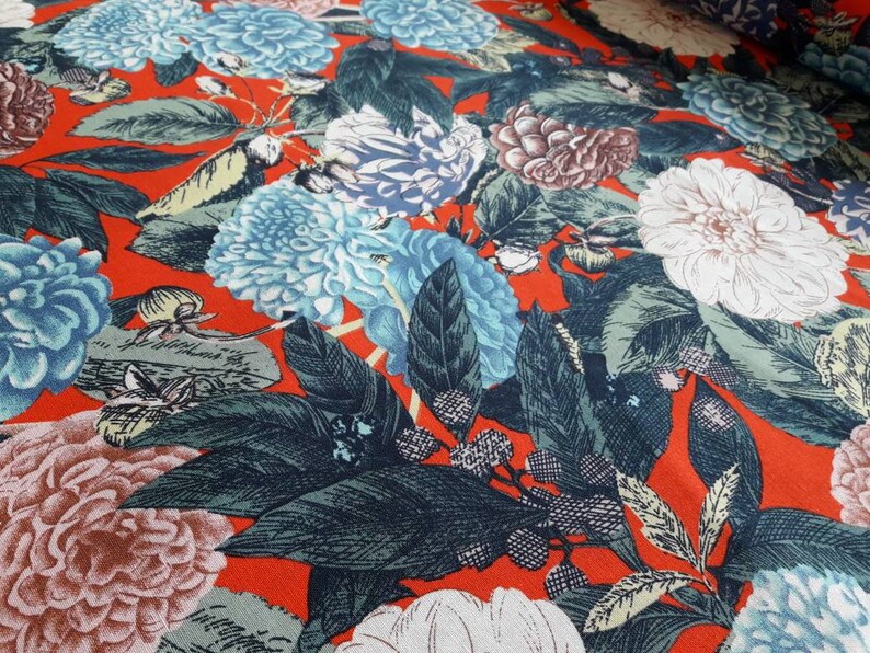 May include: Red fabric with a floral print featuring blue, white, and pink flowers with green leaves.