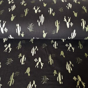 May include: Black fabric with a repeating pattern of green cactus plants. The fabric has a soft, textured feel.