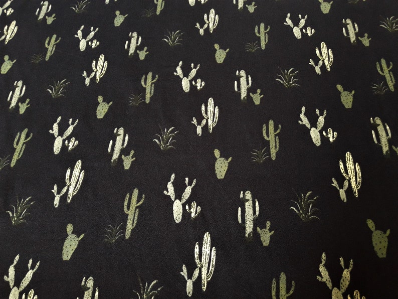 May include: Black fabric with a repeating pattern of white and green cactus silhouettes.