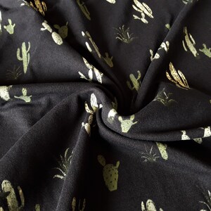 May include: Black fabric with a repeating pattern of green and yellow cacti and plants.