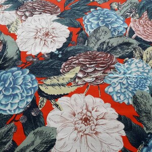 May include: Red fabric with a floral print featuring white, blue, and brown flowers. The flowers are stylized and have a vintage look.