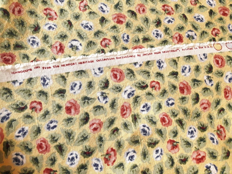 May include: Yellow fabric with a floral pattern of red, white, and blue flowers. The fabric has a white label with the text "1991 From The NEWPORT HERITAGE Collection Exclusively by JACKIE NASH ORIGINALS. Printed in the U.S.A."