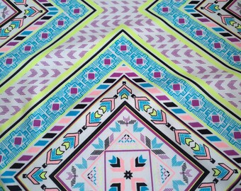 May include: A white fabric with a colorful geometric pattern. The pattern features pink, blue, green, and purple colors. The pattern is made up of repeating shapes and lines.