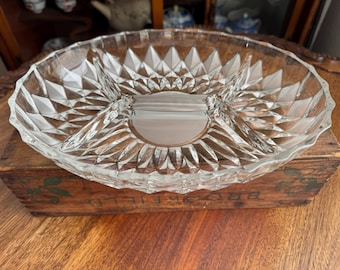 Op de afbeelding: Een glazen serveerschaal met drie verdeelde secties. De schaal heeft een diamantpatroon en staat op een houten doos.
